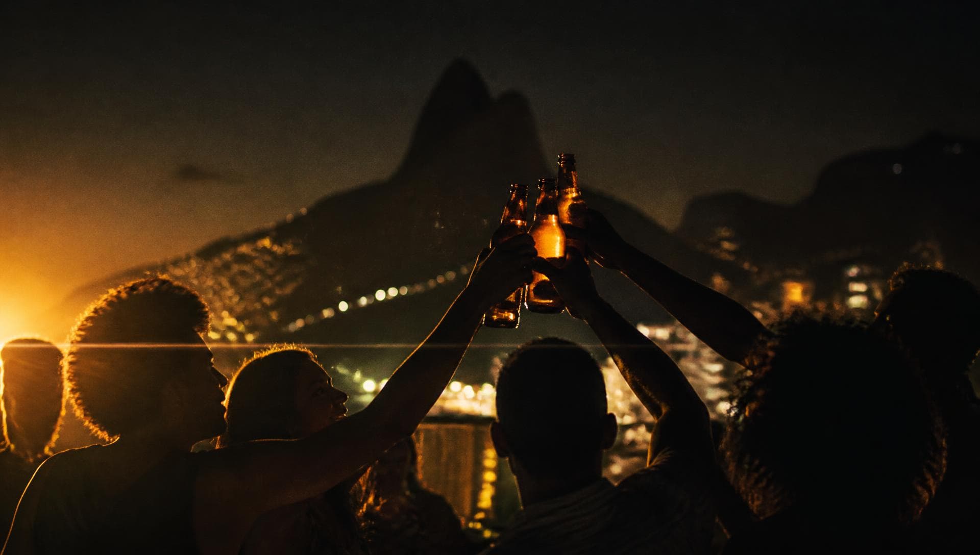 Amigos brindando com bebidas geladas em um rolê à noite